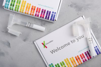 23andMe personal genetic test saliva collection kit, with tube and box on table overhead view.