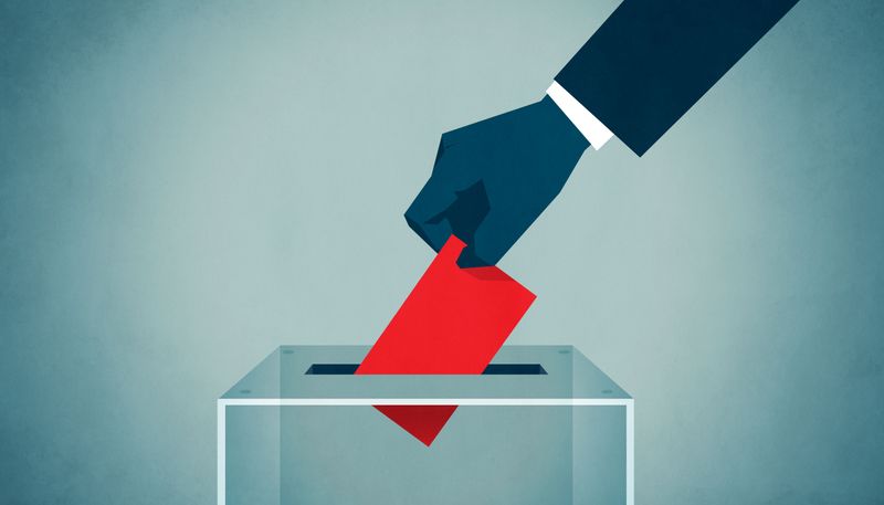 Blue hand dropping a red voting slip into a ballot box