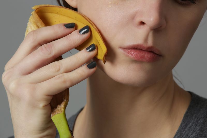 woman rubbing a banana peel on her face
