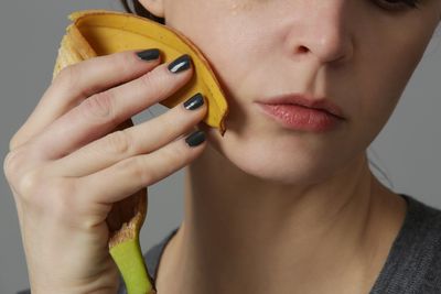 woman rubbing a banana peel on her face