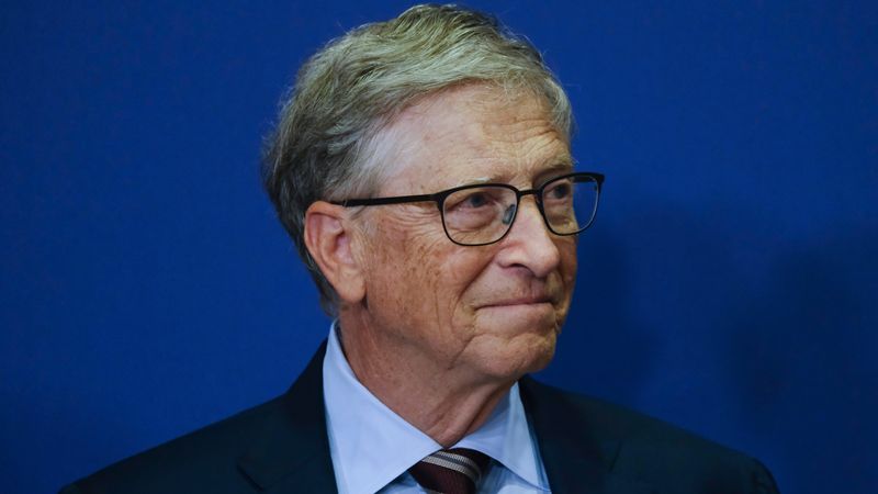 A portrait photo of Bill Gates wearing glasses and a suit and tie