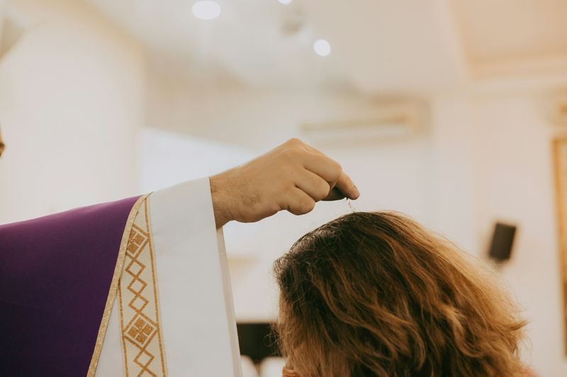 A Christian priest sprinkles water on the head of water in a church
