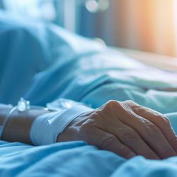 Closeup of patient's arm with IV drip in a hospital bed, symbolizing death and old age