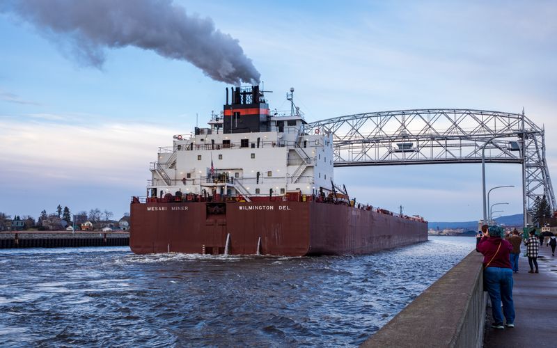 Freighter ship, the Mesabi Miner, pulls into the Duluth harbor. Large freighter showing smoke from stacks as it pulls in under lift bridge