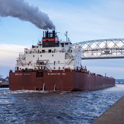 Freighter ship, the Mesabi Miner, pulls into the Duluth harbor. Large freighter showing smoke from stacks as it pulls in under lift bridge