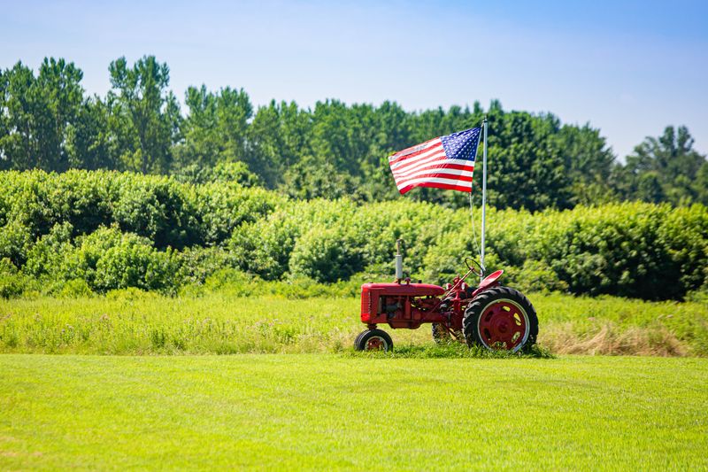 red tractor in a field flying a US flag