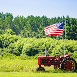red tractor in a field flying a US flag