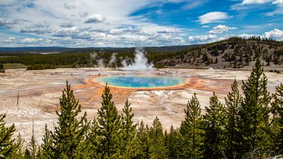 A view of a large blue pond with colorful soil in yellow and orange at its edges