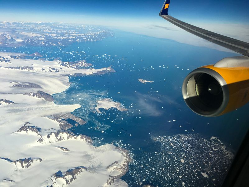 A plane flies over the icy coastline in Sermersooq Municipality, Greenland