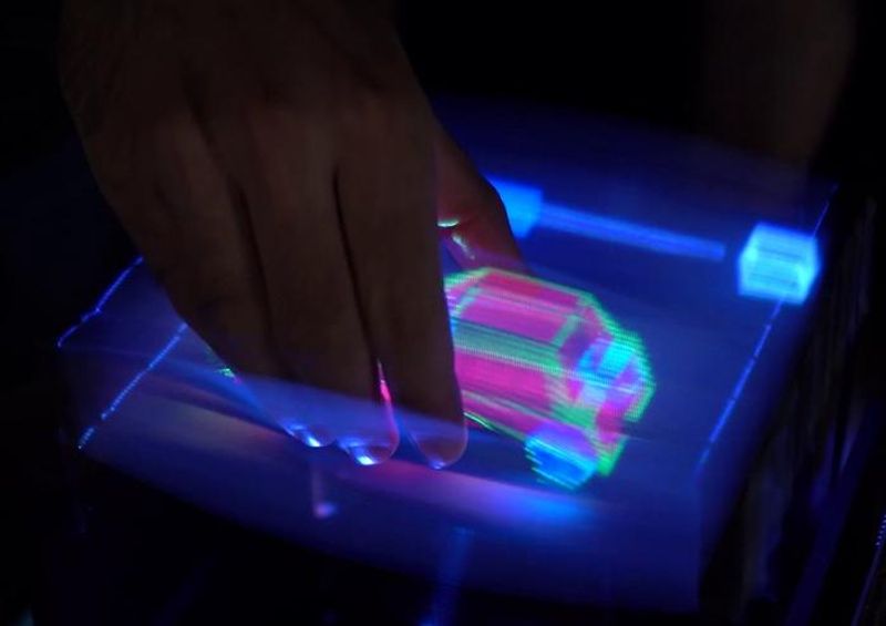 A hand is throught the display and holding onto a car made of light