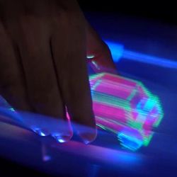 A hand is throught the display and holding onto a car made of light