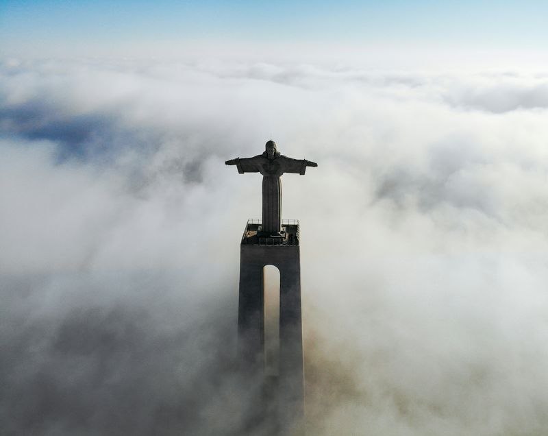 Clouds and The Sanctuary of Christ the King overlooks the city of Lisbon situated in Almada, in Portugal.