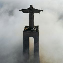 Clouds and The Sanctuary of Christ the King overlooks the city of Lisbon situated in Almada, in Portugal.