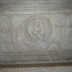 a marble slab with two crosses and a monogram withing a relied of a laurel crown. 