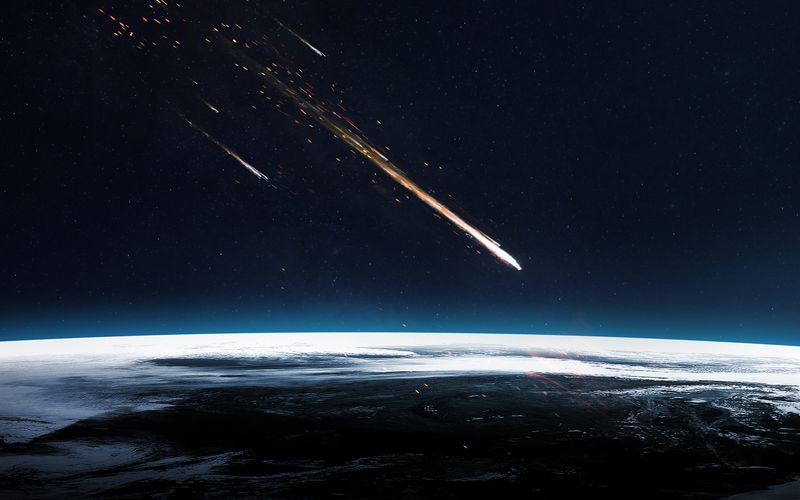 A digital photo showing a meteor about to enter the Earth's atmosphere from out of space. The perspective is from space, looking across a section of the Earth's upper limit as the streak of the comment approaches it. There is a smaller meteor in the background. 