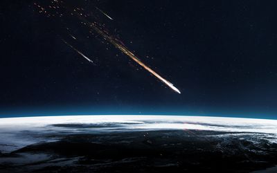 A digital photo showing a meteor about to enter the Earth's atmosphere from out of space. The perspective is from space, looking across a section of the Earth's upper limit as the streak of the comment approaches it. There is a smaller meteor in the background. 