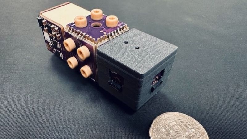 A small rectangular device next to a coin. the divice is 1 coin wide and 3 coins long