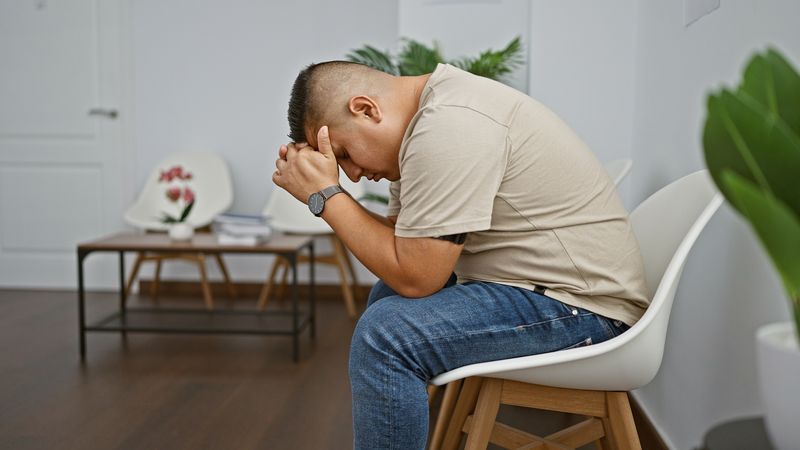 man sitting with his head in his hands in a waiting room