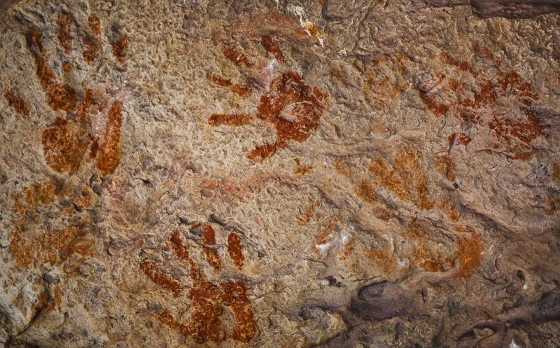 ochre handprints on a cave wall