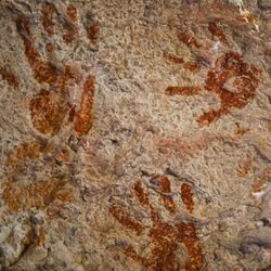 ochre handprints on a cave wall