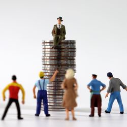 small figurines of people facing a figurine of a man in a suite and hat sitting high up on a pile of coins
