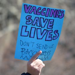 hand holding blue sign that reads "vaccines save lives, don't send us backwards." Photographed March 7 during the Stand up for Science rally against DOGE cuts to scientific research in Washington Square Park in Manhattan.