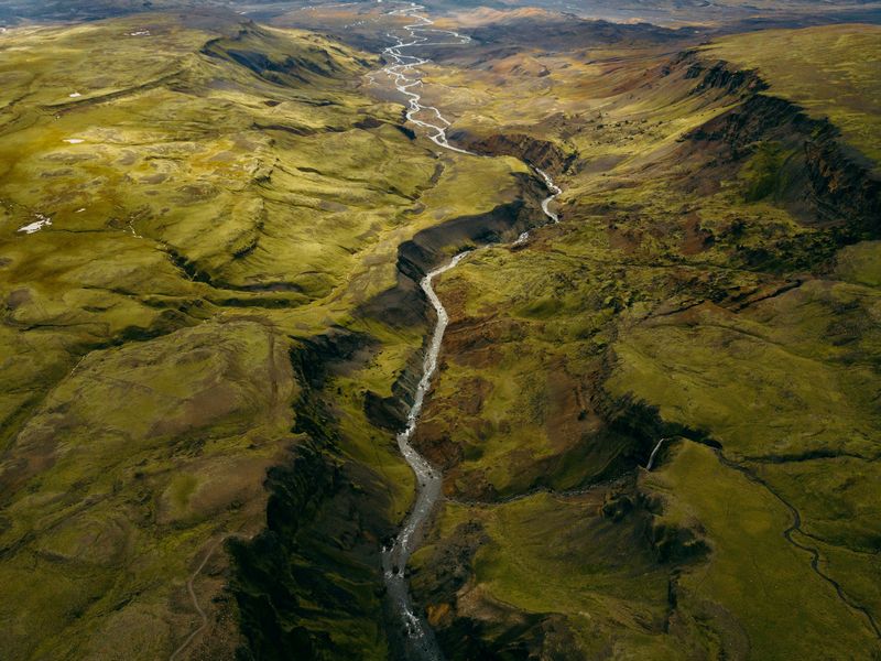 A river flowing through a rich green valley in Iceland