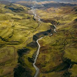 A river flowing through a rich green valley in Iceland