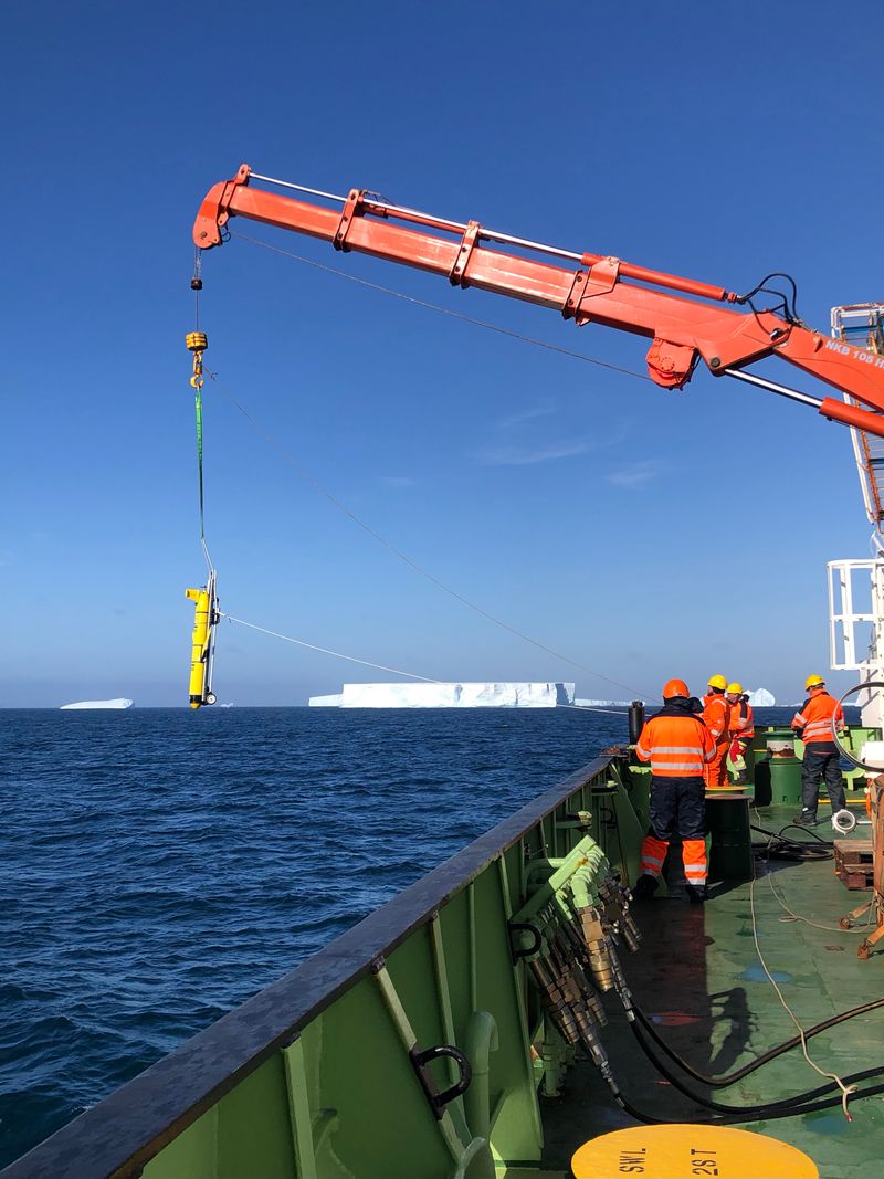 A robot glider gets hoisted off the side of the RRS James Cook boat.