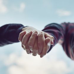 Couple holding hands shot from below with the sky in the background