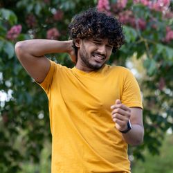 Indian young man walks in the park, does sports. Suffering from itching and mosquito bites, grimacing from discomfort