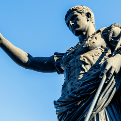 A statue of Julius Caesar, ancient Roman emperor, against a blue sky background.