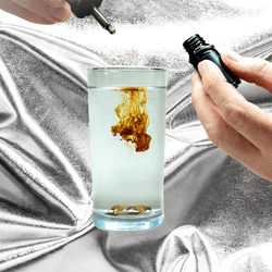 Colloidal sliver supplements being dripped into a glass of water 
