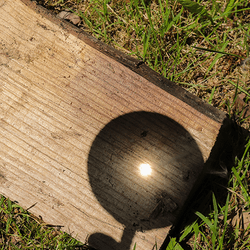 Magnifying glass focusing light onto a piece of wood.