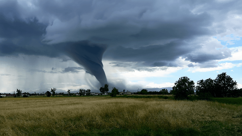 A tornado forming over farmland. 