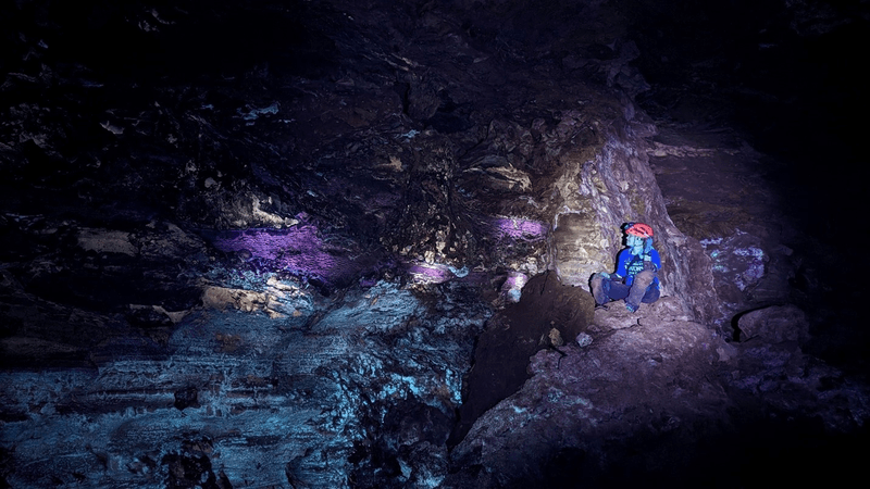 Student Jacqueline Heggen demonstrates the glow produced in Wind Cave by the minerals leached from above exposed to UV light.