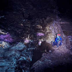 Student Jacqueline Heggen demonstrates the glow produced in Wind Cave by the minerals leached from above exposed to UV light.